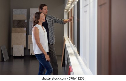 Couple Looking At Different Materials And Samples In Modern Kitchen Shop Showroom While Designing Their Dream Kitchen