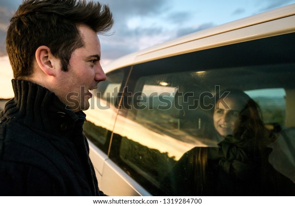 Couple looking at each other through\
the car window. Concept of happy and smiling\
relationship