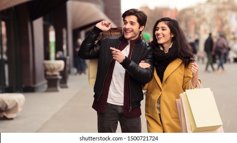 Couple looking at fashion store's window, shopping together in city center, panorama