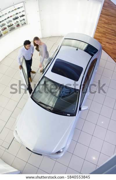 Couple\
looking inside car in a car dealership\
showroom