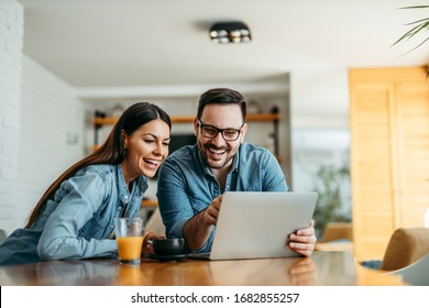 Couple Looking At Laptop Computer Together, At Home, Front View, Portrait.