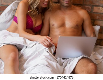 Couple looking at laptop together in bedroom