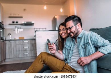 Couple Looking At Mobile Phone At Home.