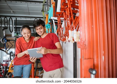 A Couple Looking New Model Of Bike On Tablet Screen When Standing