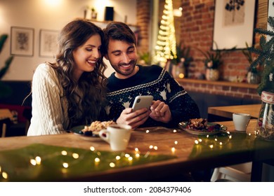 Couple looking at phone together while in cafe during christmas time - Powered by Shutterstock