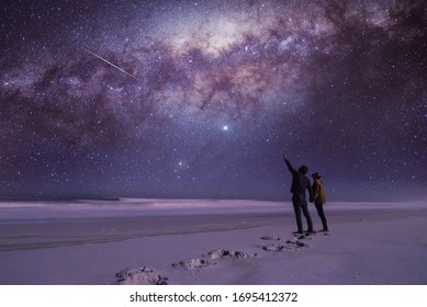 Couple looking and pointing in amazement at a shooting star.