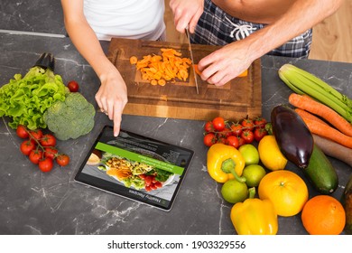 Couple looking at recipe on tablet and preparing meal