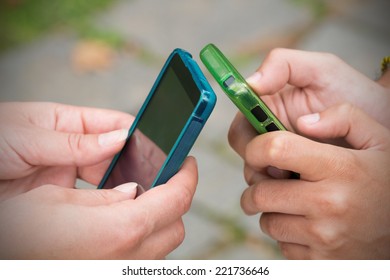 Couple looking at their smart-phones while sitting in a park.  - Shutterstock ID 221736646