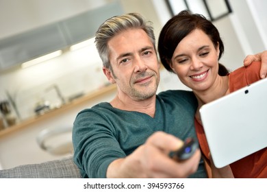 Couple looking at tv program on digital tablet