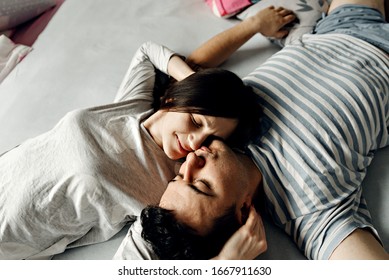 couple  love in bed,happy young family wakes up early in the morning in bed,top view of a couple who wakes up,husband and wife are smiling and hugging tenderly,peeping on the couple who is on the bed