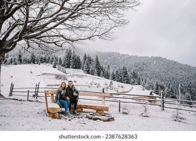 Couple in love with blanket hugs in winter on hill near wood forest. Man and woman holding cup drinking coffee. Recreation area, fire pit, fireplace in backyard house. Cabin terrace with mountain view - Powered by Shutterstock