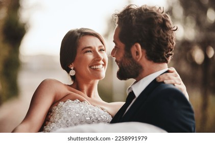 Couple, love and bonding at wedding, marriage event or ceremony vows, union or commitment in sunset nature park. Smile, happy and groom carrying bride in celebration, security or partnership support