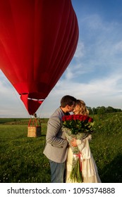 Couple In Love With Bouquet Of Red Roses Kissing On Hot Air Ballon Background. Romantic Date, Marriage Proposal And Honeymoon