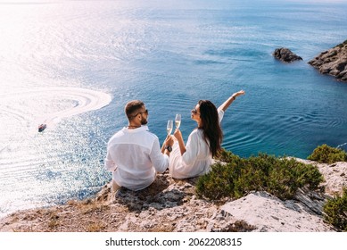 A couple in love celebrates their engagement on the seashore. A beautiful couple drinks champagne by the sea. Honeymoon trip. Lovers on the beach. Wedding travel. Couple on vacation. Copy space - Shutterstock ID 2062208315