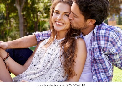 Couple, love and cheek kiss on love date, nature grass or garden park on valentines day, romance bonding or summer. Smile, happy woman and man hug in relax environment, support or partnership picnic