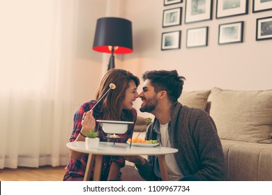 Couple in love dipping fruit into melted chocolate, relaxing and enjoying romantic moments together