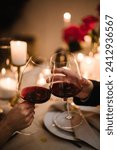 Couple in love drinking wine. Cheers. Romantic date by candlelight at night. Hands man and woman hold glasses at home. Toast. Dinner setup table for couple on Valentine
