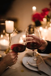 Couple In Love Drinking Wine. Cheers. Romantic Date By Candlelight At Night. Hands Man And Woman Hold Glasses At Home. Toast. Dinner Setup Table For Couple On Valentine's Day. Proposal Hand And Heart.