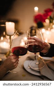 Couple in love drinking wine. Cheers. Romantic date by candlelight at night. Hands man and woman hold glasses at home. Toast. Dinner setup table for couple on Valentine's day. Proposal hand and heart.