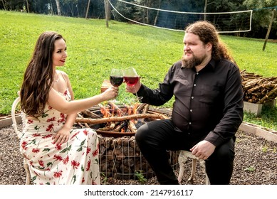 Couple In Love Drinking Wine In Front Of A Bonfire In The Garden