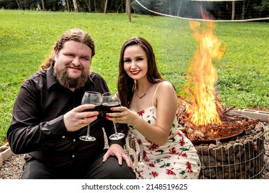 Couple In Love Drinking Wine In Front Of A Bonfire In The Garden