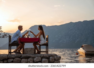 Couple in love drinking wine on romantic dinner at sunset on the beach. People love travel concept - Powered by Shutterstock