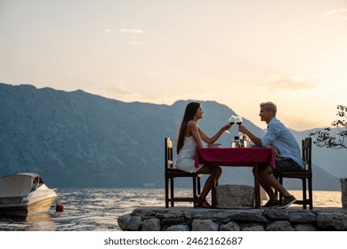 Couple in love drinking wine on romantic dinner at sunset on the beach. - Powered by Shutterstock