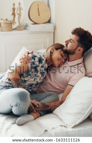 Couple in love is embracing on the bed. Man hugging and kissing his girlfriend