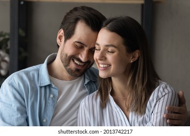 Couple in love embracing sit together on sofa. Loving handsome husband touch foreheads with beloved wife, feeling bond enjoy tender moment. Romantic relations, care, happy marriage, harmony concept