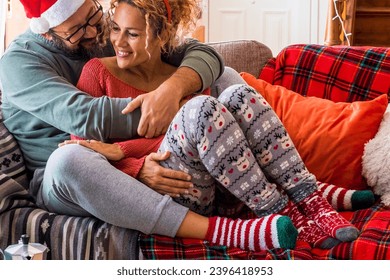 Couple in love enjoy romantic leisure activity during christmas holiday celebration season. Man hugging woman  both sitting on the sofa. Happy wife and husband with xmas decorations at home. Relax - Shutterstock ID 2396418953