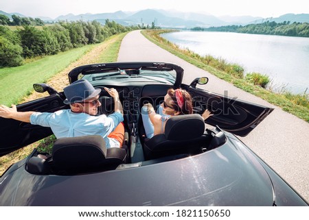 Couple in love getting into the convertable auto and starting a trip. Couple honeymoon or vacation concept image.