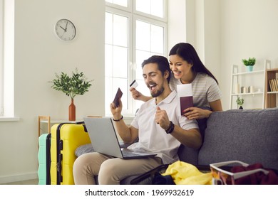 Couple In Love Getting Ready For Holiday Trip Using Airline Website To Book Tickets Online. Happy Man And Woman Excited About Travel Vacation Abroad Sitting On Couch At Home Looking At Laptop Screen