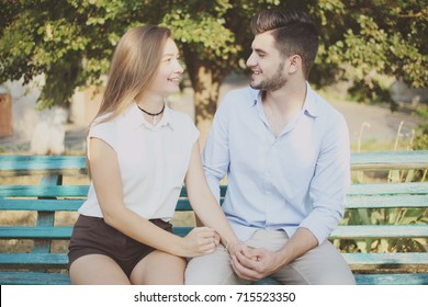 A couple in love: a guy and a girl are sitting on a bench in the background of nature.