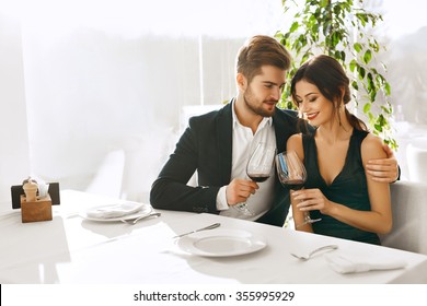 Couple In Love. Happy Romantic Smiling Elegant People Having Dinner, Drinking Wine, Celebrating Holiday, Anniversary Or Valentine's Day In Gourmet Restaurant. Romance, Relationships Concept.