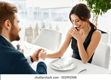 Couple In Love. Happy Smiling Elegant Young People Celebrating Anniversary Or Valentine's Day And Having Romantic Dinner Or Lunch Together In Gourmet Restaurant. Romance, Relationships Concept.