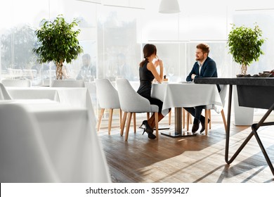Couple In Love. Happy Smiling Elegant Young People Celebrating Anniversary Or Valentine's Day And Having Romantic Dinner Or Lunch Together In Gourmet Restaurant. Romance, Relationships Concept.