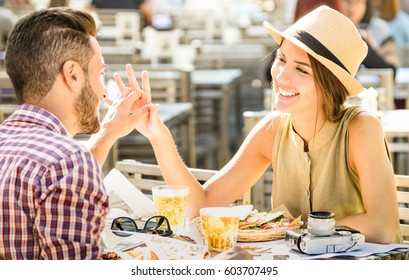 Couple in love having fun at beer bar on travel excursion - Young happy tourists enjoying tender moment at street food restaurant - Relationship concept with focus on girl face on warm bright filter