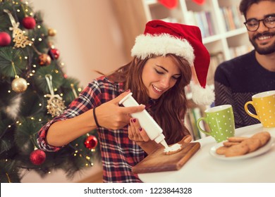 Couple in love having fun on Christmas morning, decorating Christmas cookies and drinking coffee - Powered by Shutterstock