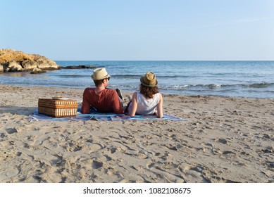 Couple in love having a picnic on a mediterranean beach at sunset