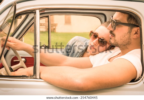 Couple in love having a rest during honeymoon\
vintage car trip - Hipster lifestyle traveling around the world\
with classic car - Young people enjoying happy moments of life -\
Warm retro filtered look