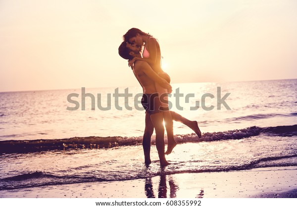 Couple in love having romantic tender moments at
sunset on the beach - Young lovers having tender moments in summer
vacation - Love concept - Soft focus on them - Matte filter with
soft blue vignette