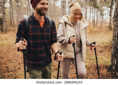 Couple In Love Hiking Together In A Pine Forest, Using Trekking Poles. Millennial Hipsters Travelers Spending Time Together.