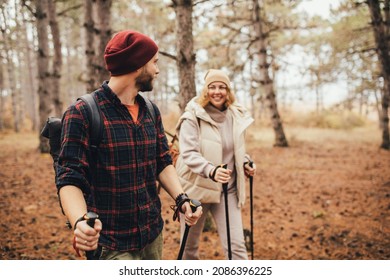 Couple In Love Hiking Together In A Pine Forest, Using Trekking Poles. Millennial Hipsters Travelers Spending Time Together.