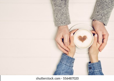 Couple in love holding hands with coffee on white wooden table. Photograph taken from above, top view with copy space - Powered by Shutterstock