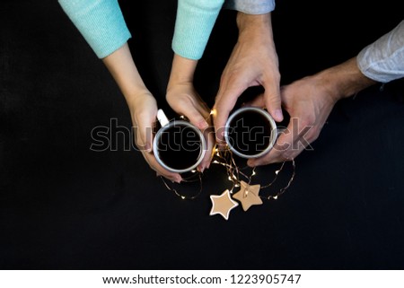 Couple in love holding hands with coffee on black table. Photograph taken from above, top view with copy space. Toned
