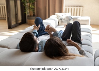 Couple in love holding hands relaxing lying on comfy modern sofa in warm cozy living room, enjoy conversation share dreams daydreaming together about happy joint future, cohabitation. Tenancy concept