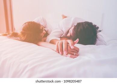 Couple in love holding hands sleep in the bed with sunlight in the morning