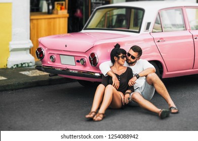 Couple in love hugging at the car. Couple resting on the car. Beautiful bearded man and attractive young woman in an old classic car. Stylish love story. Hugging and kissing in the car. Wedding travel