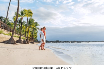 Couple in love hugging on sandy exotic beach while having evening walk by Trou-aux-Biches seashore on Mauritius island enjoying sunset. People relationship and tropic honeymoon vacations concept image - Powered by Shutterstock