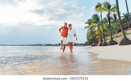 Couple in love hugging while walking on a sandy exotic beach. They have an evening walk by Trou-aux-Biches seashore on Mauritius island. People relationship and tropic honeymoon vacations concept